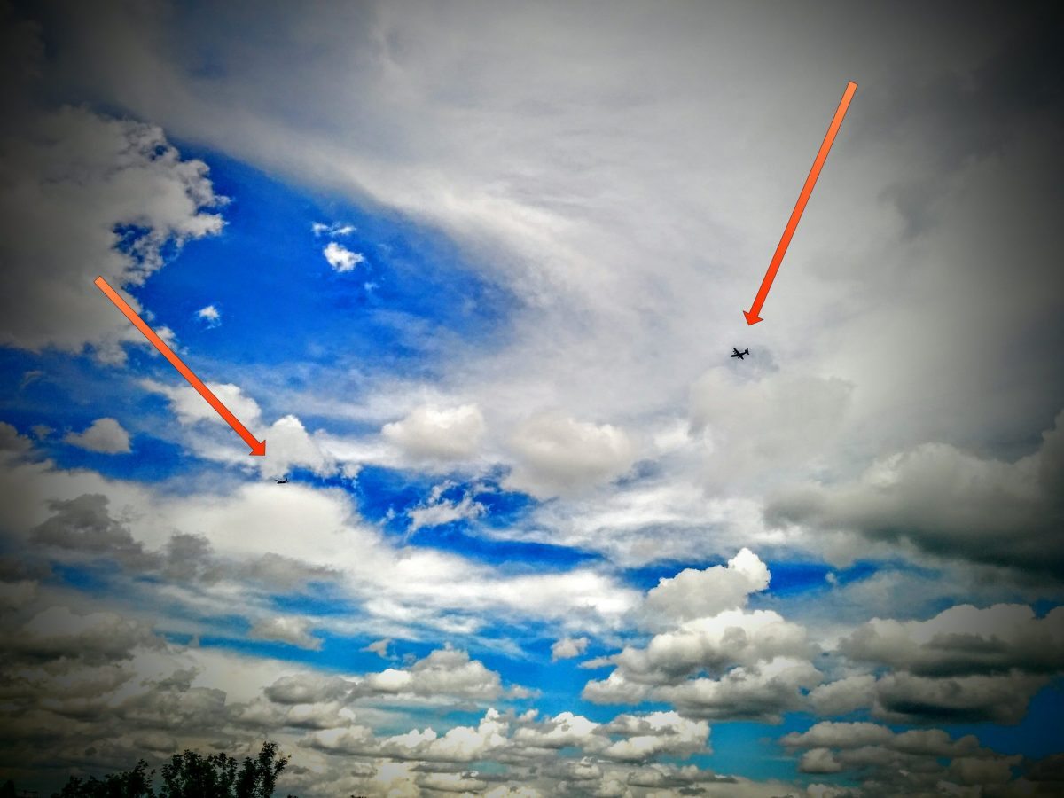 Bild zeigt Wolkenhimmel über Regensburg mit zwei Pfeilen die auf Transportflugzeuge zeigen