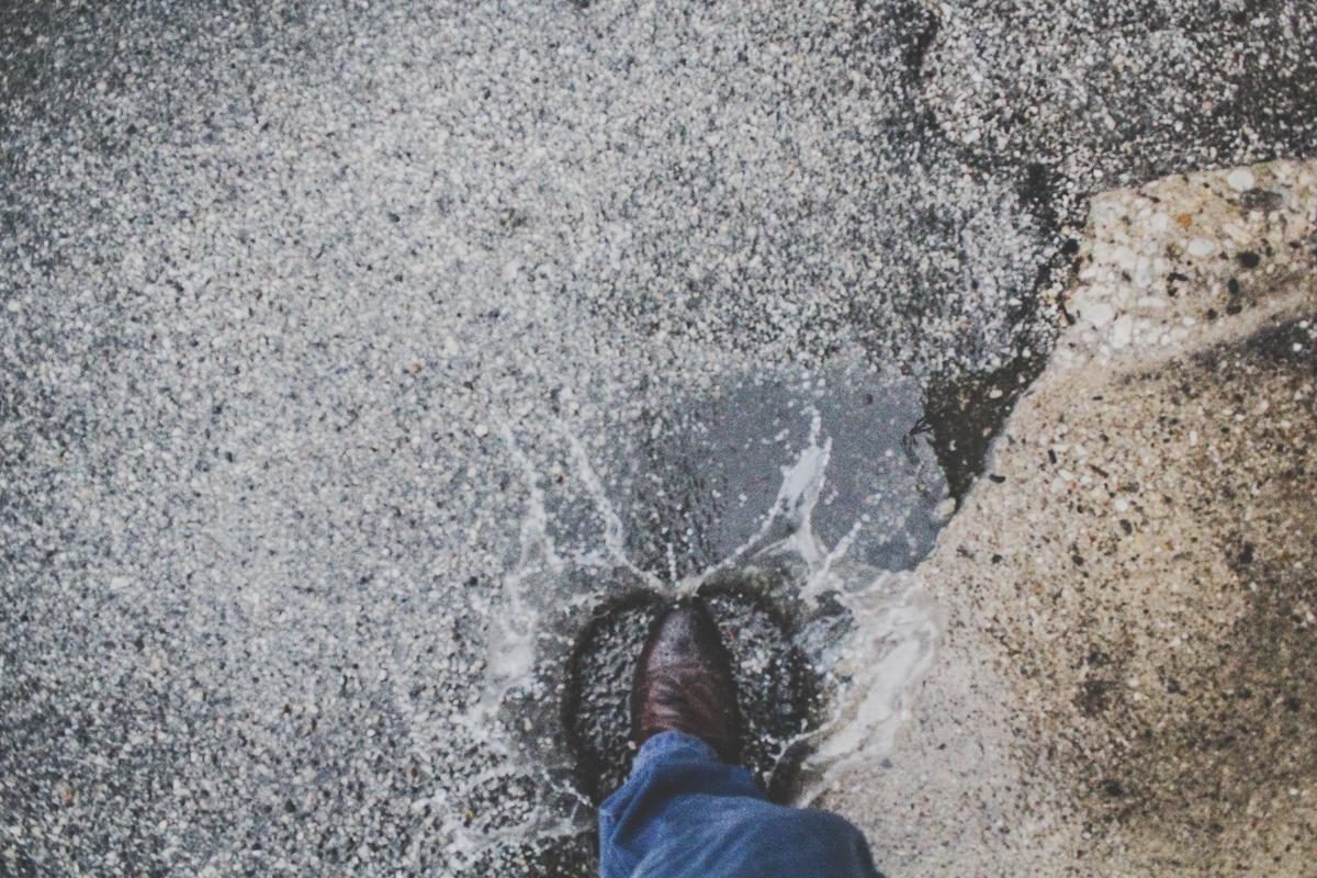 Photo of a man walking into a puddle; by EricThriller via unsplash